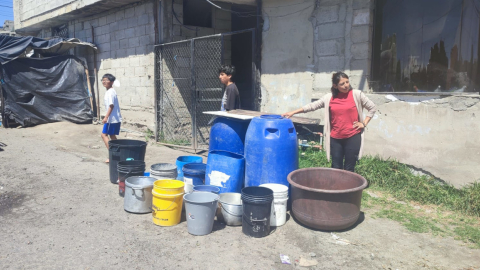 Cristina González junto a baldes de agua, a la espera de un tanquero, el 24 de abril de 2024, en Quito.