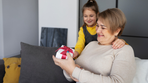 Una niña entregando un regalo a su abuela en el Día de las Madres.