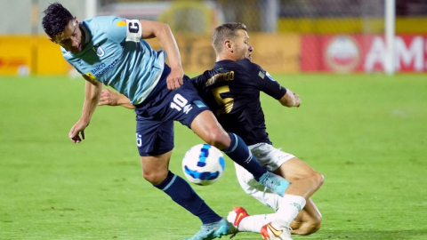 Facundo Martínez de Universidad Católica y Nicolás Domingo del Banfield de Argentina se disputan el balón durante un partido.