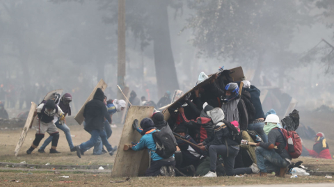 Manifestantes se resguardan atrás de escudos de madera durante las protestas del domingo 13 de octubre de 2019.