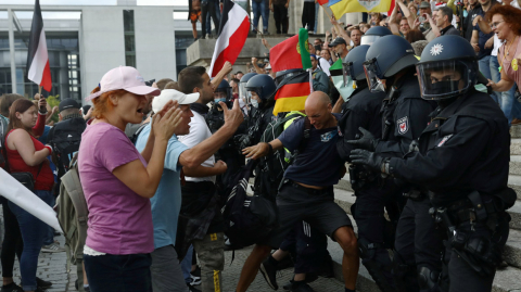 Police officers scuffle with a protester in front of the Reichstag Building during a rally against the government's restrictions following the coronavirus disease (COVID-19) outbreak, in Berlin, Germany, August 29, 2020. REUTERS/Christian Mang