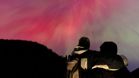 Una pareja observa una aurora boreal, el 11 de mayo de 2024 en Manning Park, Columbia Británica, Canadá.