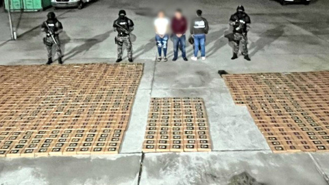 Policías posan junto a dos detenidos y un millar de paquetes de cocaína decomisados en Daule, el 24 de mayo de 2024.