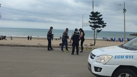 Miembros de la Policía Nacional realizan el levantamiento de un cadáver, en la playa de Jaramijó.