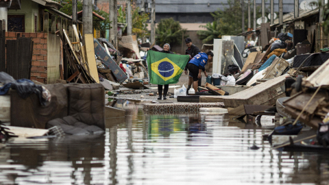 Una mujer sostiene una bandera de Brasil en medio de una calle afectada por las inundaciones, este lunes 3 de junio en Porto Alegre, Rio Grande do Sul (Brasil).