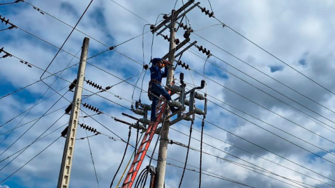 Funcionario de CNEL realiza trabajos en los postes de luz.