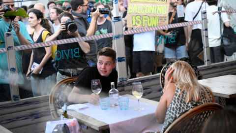 Manifestantes ponen una cinta simbólica en la ventana de un restaurante en Barcelona, el 6 de julio de 2024 durante unas protestas en contra del turismo masivo.