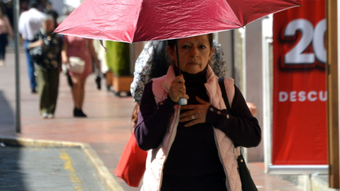 Una mujer camina con una sombrilla para protegerse del calor, el 26 de enero de 2024.