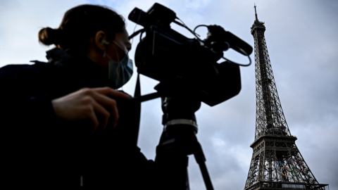 Un periodista filma frente a la Torre Eiffel, decorada con los anillos olímpicos de los próximos Juegos Olímpicos de París, el 17 de junio de 2024.