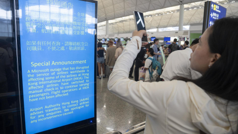 Una mujer toma fotografías a un anuncio sobre el fallo de Microsoft en un aeropuerto de Hong Kong, el 19 de julio de 2024.