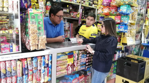 Una funcionaria del SRI entrega información sobre la remisión tributaria a locales comerciales en Guaranda, provincia de Bolívar. Imagen referencial.