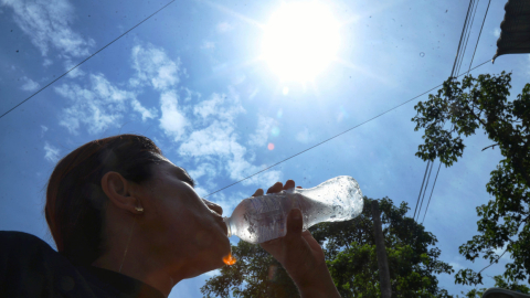 Una mujer se hidrata ante el intenso sol en Ecuador.