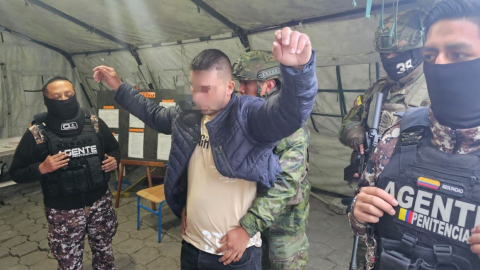 Policías y militares inspeccionan a un presunto guerrillero detenido en Carchi el 13 de agosto de 2024.