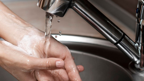 Una persona se lava las manos en una llave de agua potable.