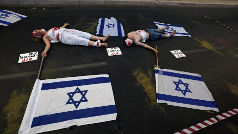 Personas en el suelo junto a banderas de Israel y manchas de sangre falsa pide la liberación de rehenes israelíes secuestrados por jamás, el 31 de agosto de 2024 en Tel Aviv, Israel.