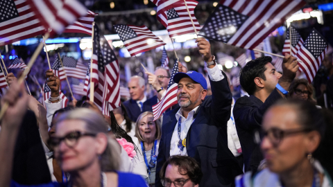 Asistentes a la Convención Demócrata Nacional ondean banderas de Estados Unidos en el United Center, en Chicao, Illinois, el 22 de agosto de 2024.