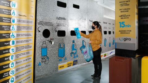 Mujer en contenedor de reciclaje de GIRA depositando una funda plástica.