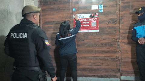 Una funcionaria de la Agencia Metropolitana de Control pone un cartel de clausurado en una clínica clandestina ubicada en un barrio del sur de Quito, el 14 de septiembre de 2024.