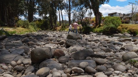 Una pareja atraviesa caminando el lecho seco de río Tomebamba, en Cuenca (Azuay), el pasado 18 de septiembre de 2024, en una ciudad que registra la peor sequía décadas.