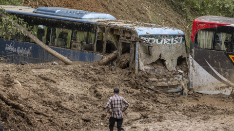 Un hombre mira buses de pasajeros enterrados por deslaves en Jhayple Khole, Distrito de Dadhing, Nepal, el 29 de septiembre de 2024.