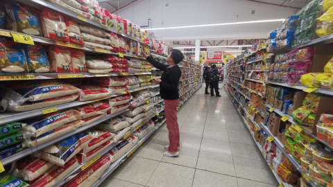 Una persona revisa productos en la percha de un supermercado, en el norte de Quito, septiembre de 2023. Imagen referencial.