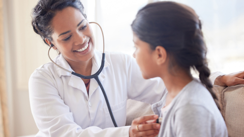 Médico examinando a una niña con un estetoscopio.