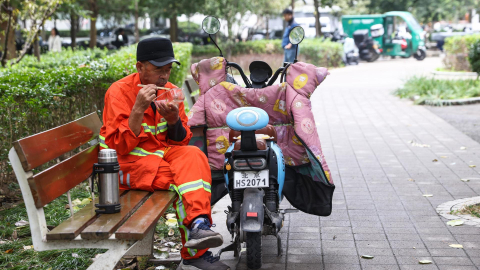 Un hombre de tercera edad come en una calle de Pekín, capital de China, el 18 de octubre de 2024.