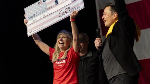 El fundador de SpaceX y Tesla, Elon Musk, entrega un cheque de USD 1 millón  a Kristine Fishell durante un evento de campaña en Harrisburg, Pensilvania, el 20 de octubre de 2024.