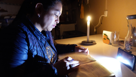 Una mujer lee con una vela durante los cortes de luz en Cuenca, en octubre de 204.