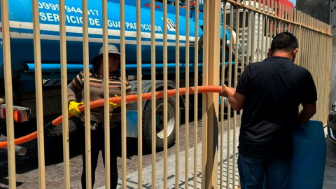 Morador recibe agua potable por medio de un tanquero en Quito.