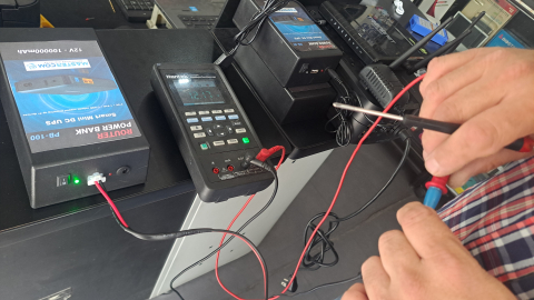 El ingeniero Edgar Ortiz muestra a la cámara el voltaje que entrega un 'power bank' inventado y fabricado por el mismo, en su negocio ubicado en la avenida Colón de Quito.