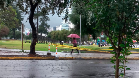 Ciudadana camina con un paraguas por el parque de La Carolina, en el norte de Quito.