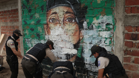 Policías borran un mural alusivo a bandas criminales en el Suburbio de Guayaquil, en el distrito Portete, afectado por enfrentamientos entre los grupos Los Duendes y Freddy Kruger's.