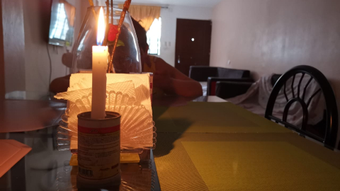 Imagen referencial de una mujer comiendo a la luz de las velas en medio de la crisis eléctrica y de cortes programados que vive Ecuador.