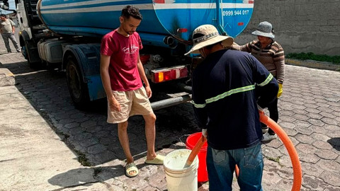 Morador de Quito recibe agua potable mediante un tanquero.