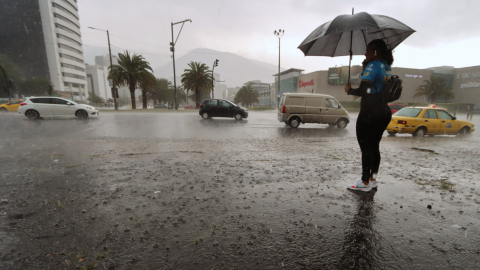 Una mujer con un paraguas bajo la lluvia en Quito