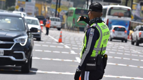 Agente de tránsito dirige el tráfico en una avenida de Quito.