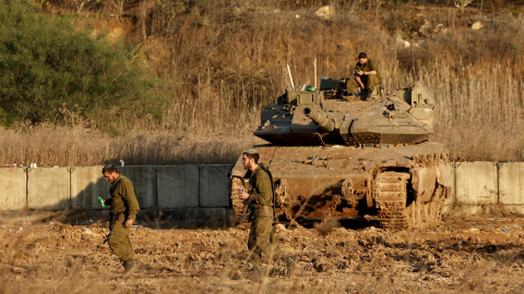 Soldados israelís caminan delante de un tanque en Metula, al norte de Israel, el 28 de noviembre de 2024, tras un acuerdo de alto el fuego con Hezbollah.