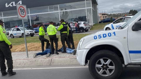 Elementos de la Policía Nacional retienen a dos sospechosos, después que un guía penitenciario es asesinado en Latacunga, el 29 de noviembre de 2024.