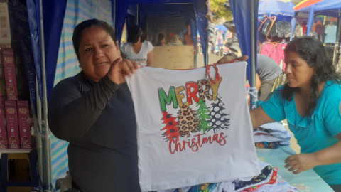 Blanca Costa, de 48 años, muestra una pijama navideña que vende en uno de los corredores navideños instalados para los comerciantes de Guayaquil. 12 de diciembre del 2024.