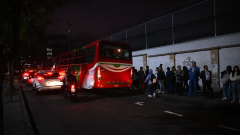 Personas esperan el bus en una calle de Quito