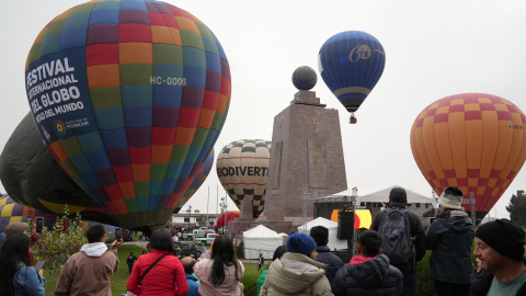 Personas observan globos aerostáticos durante el Festival Internacional del Globo en la Mitad del Mundo, en Quito (Ecuador). Durante el Tercer Festival Internacional del Globo, cientos de asistentes tuvieron la oportunidad de admirar y fotografiar la majestuosidad de los globos, junto con una variada oferta cultural. EFE/ Vicente Costales