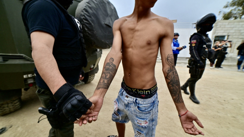 Un agente de policía comprueba los tatuajes de un hombre durante una operación conjunta de las Fuerzas Armadas y la Policía Nacional en el cantón Durán, el 9 de diciembre de 2024.