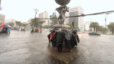 Personas se resguardan de la lluvia en Quito