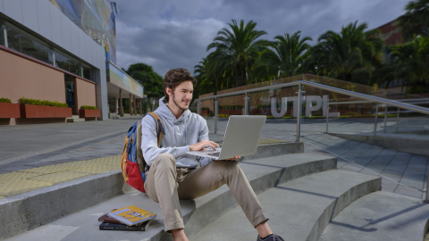 Estudiante de la UTPL con laptop en las instalaciones de la institución