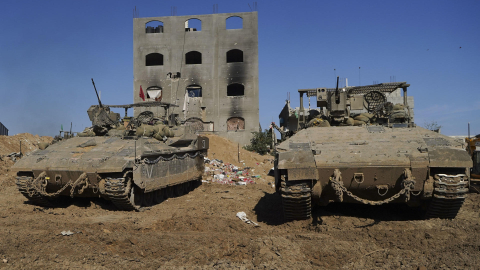 Un edificio con daños en Yabalia, norte de la Franja de Gaza, detrás de tanques israelíes que recorren la zona, el 8 de enero de 2025.