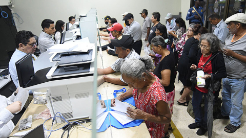 Fotografía referencial de ciudadanos que pagan tributos municipales en ventanillas físicas en Guayaquil.