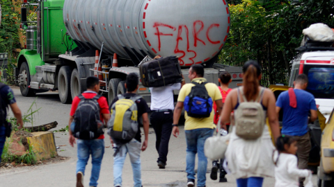 Fotografía de archivo de personas caminando junto a un camión con la frase "FARC 33" en la Vereda Santa Rosa, en Catatumbo (Colombia).