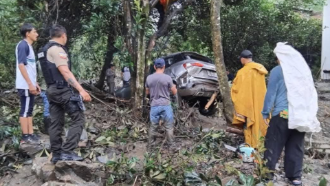 Personas miran un vehículo arrastrado por un desbordamiento en Loja