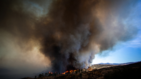 Las llamas suben por la colina mientras la columna de humo del incendio Hughes llena el cielo en Castaic, 22 de enero de 2025.